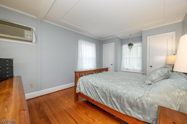 bedroom featuring baseboards, multiple windows, wood finished floors, and ornamental molding