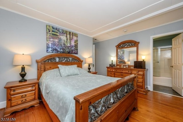 bedroom featuring ensuite bath and light wood-style floors