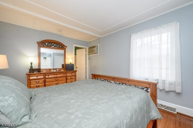 bedroom with wood finished floors, baseboards, visible vents, a wall mounted AC, and crown molding