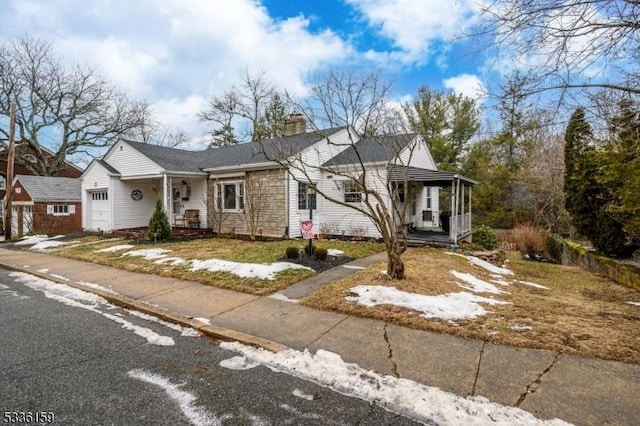 view of front of home featuring covered porch, an attached garage, and a chimney