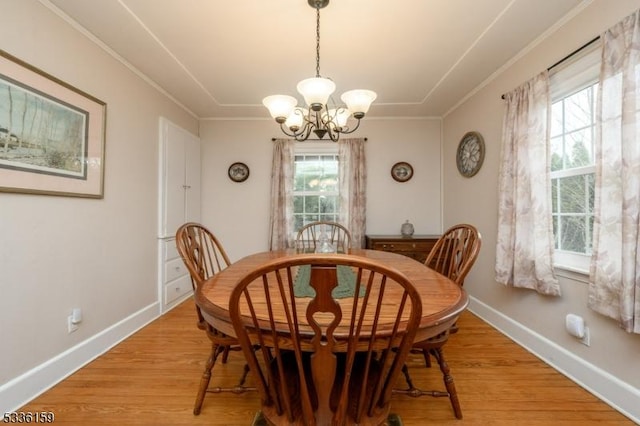 dining room with a chandelier, baseboards, crown molding, and light wood-style floors