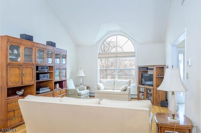 living room with high vaulted ceiling, a baseboard heating unit, and light hardwood / wood-style floors