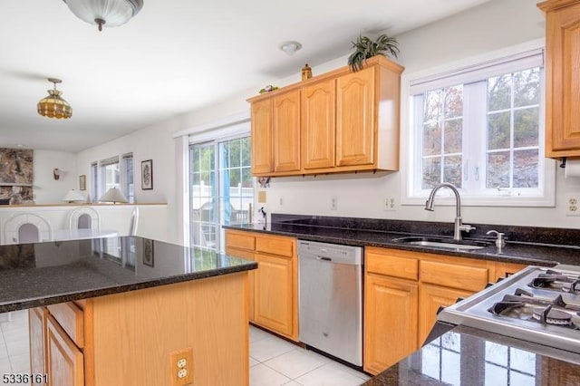 kitchen with dark stone countertops, sink, stainless steel dishwasher, and a center island