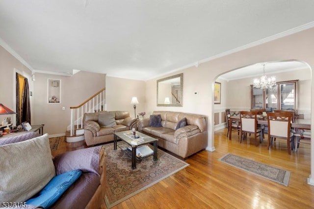 living room with an inviting chandelier, crown molding, and light hardwood / wood-style floors