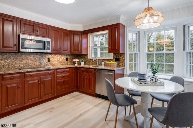 kitchen featuring appliances with stainless steel finishes, decorative light fixtures, sink, backsplash, and light stone counters