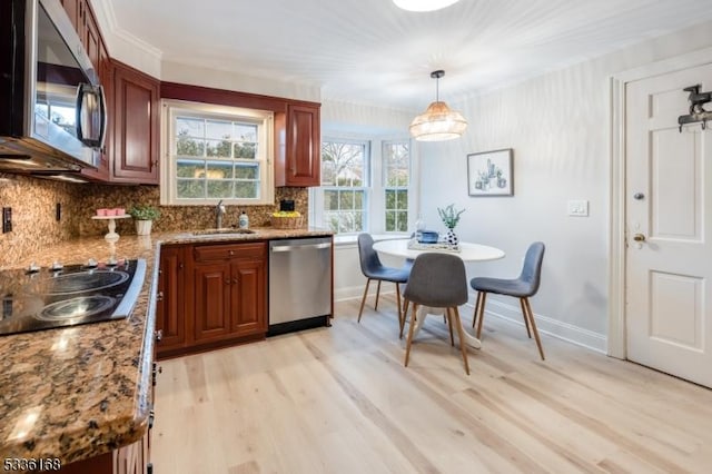 kitchen with sink, hanging light fixtures, light hardwood / wood-style flooring, appliances with stainless steel finishes, and decorative backsplash