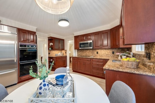 kitchen with sink, backsplash, light stone counters, black appliances, and crown molding