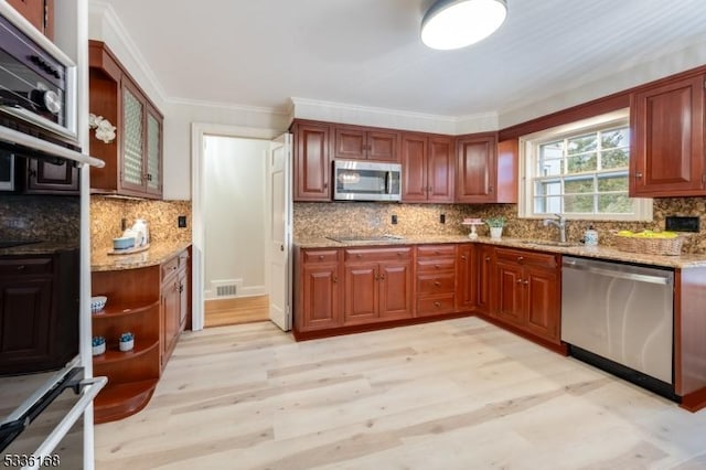 kitchen with tasteful backsplash, light stone countertops, appliances with stainless steel finishes, and sink