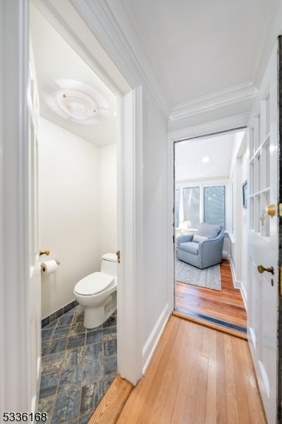 bathroom featuring hardwood / wood-style floors, crown molding, and toilet