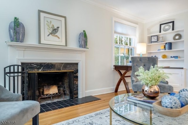 living area featuring crown molding, wood-type flooring, and a high end fireplace