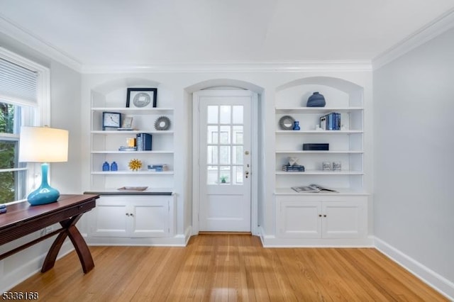 doorway to outside with ornamental molding, light hardwood / wood-style floors, and built in features