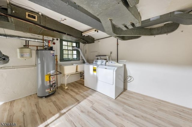 laundry room with light hardwood / wood-style flooring, washer and dryer, and gas water heater