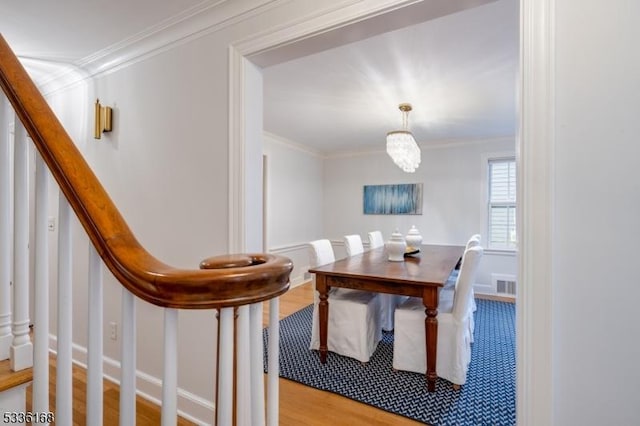 dining space with an inviting chandelier, crown molding, and light hardwood / wood-style flooring