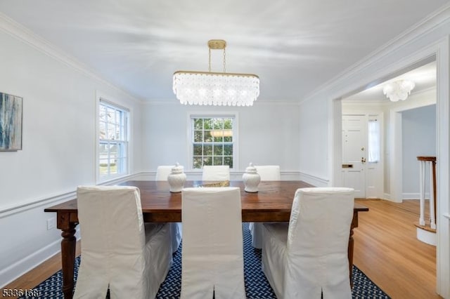 dining area with crown molding, a notable chandelier, and light wood-type flooring