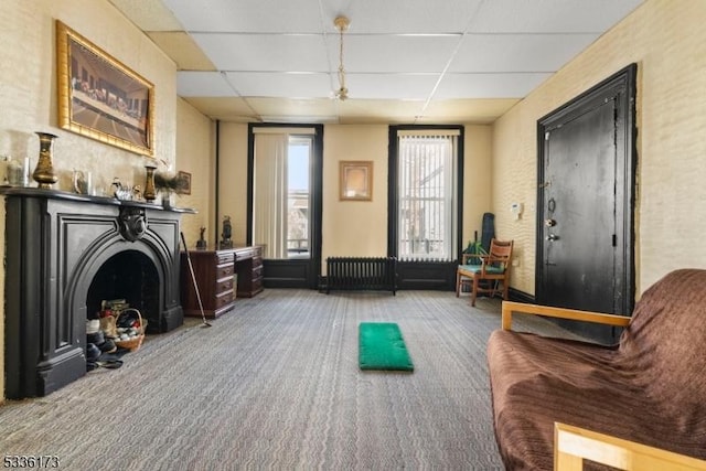 interior space with carpet, radiator heating unit, and a drop ceiling