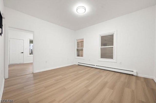 spare room with a baseboard heating unit and light hardwood / wood-style floors