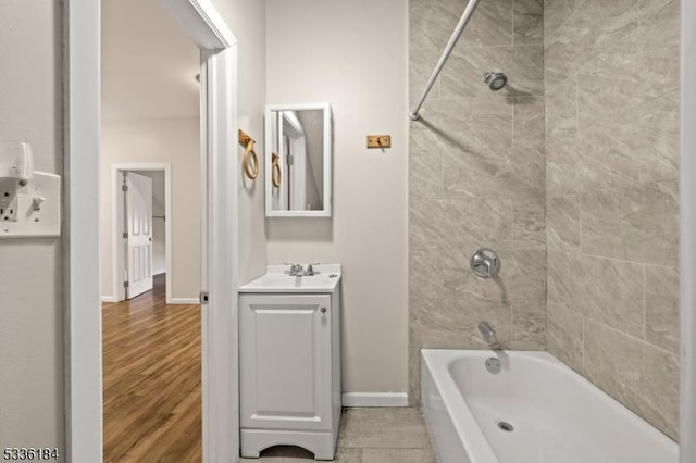 bathroom with hardwood / wood-style flooring, tiled shower / bath, and vanity