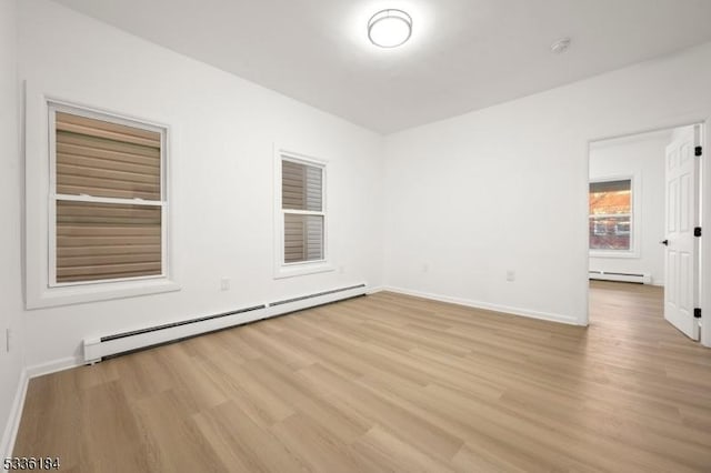 unfurnished room with a baseboard radiator and light hardwood / wood-style floors