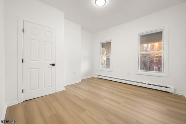 spare room with baseboard heating and light hardwood / wood-style flooring