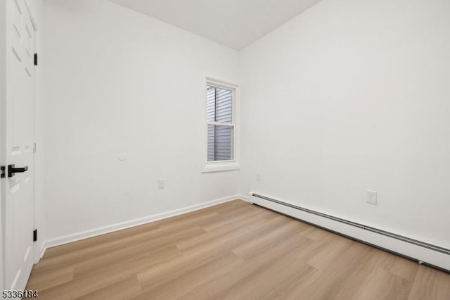 unfurnished room with baseboard heating and light hardwood / wood-style flooring