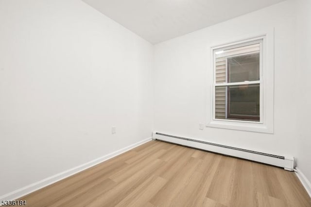 unfurnished room featuring baseboard heating and light hardwood / wood-style flooring