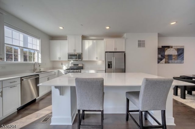 kitchen featuring sink, a breakfast bar area, appliances with stainless steel finishes, white cabinetry, and a kitchen island