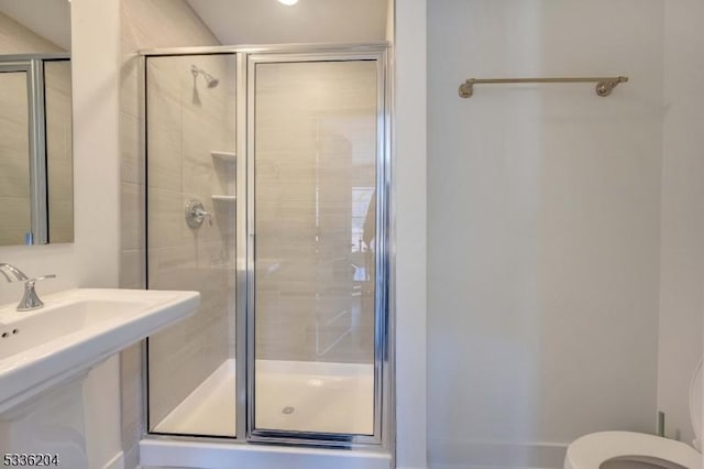 bathroom with sink, a shower with shower door, and toilet