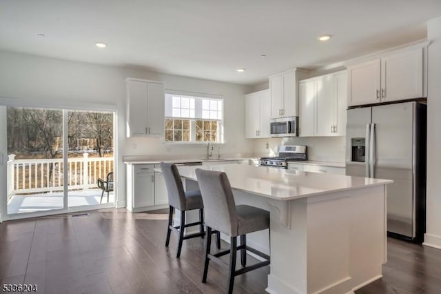 kitchen featuring stainless steel appliances, white cabinetry, a center island, and dark wood-type flooring