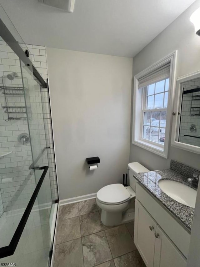 bathroom with vanity, a shower with shower door, and toilet