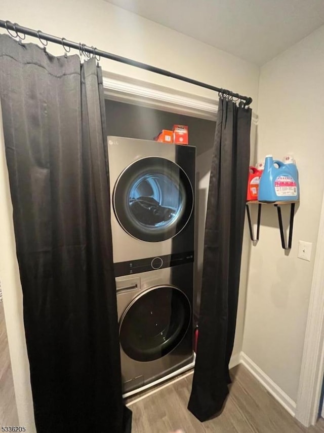 laundry room featuring wood-type flooring and stacked washer / drying machine