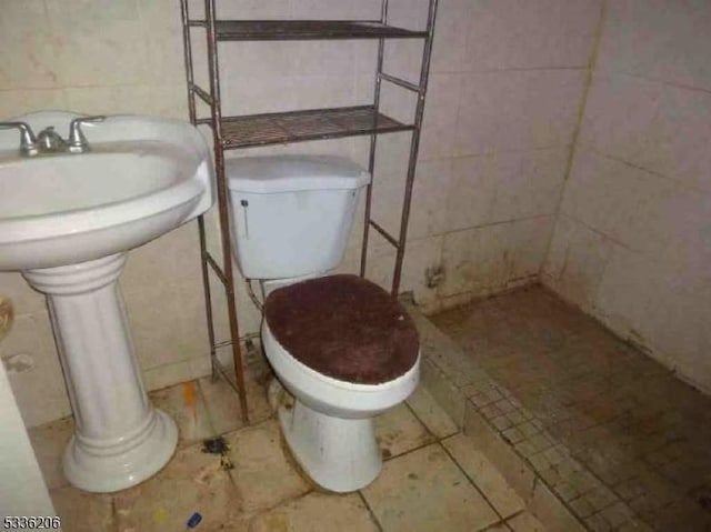 bathroom with toilet and tile walls