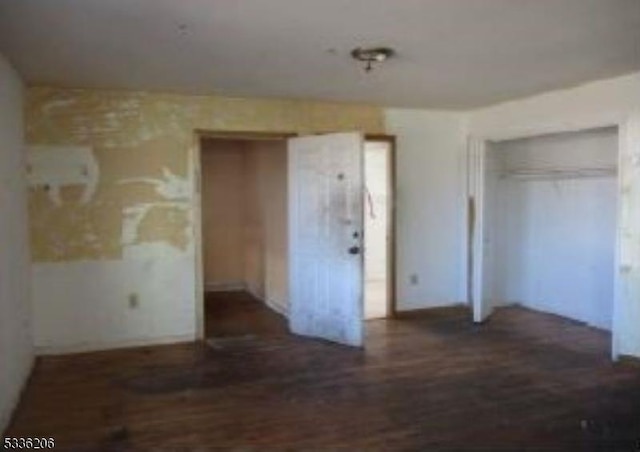 unfurnished bedroom featuring dark wood-type flooring and two closets