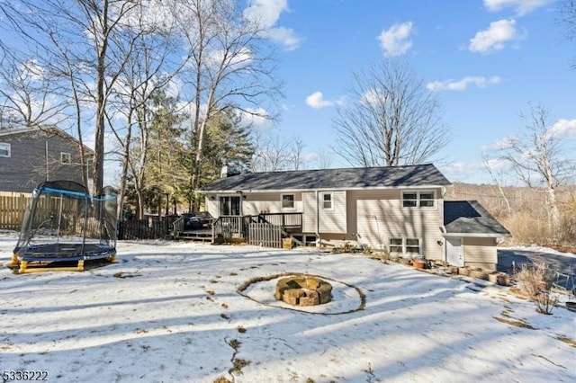 snow covered property featuring a trampoline, a fire pit, and a deck