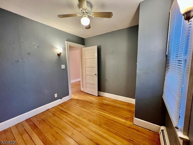 unfurnished room featuring ceiling fan, light hardwood / wood-style flooring, and a baseboard heating unit