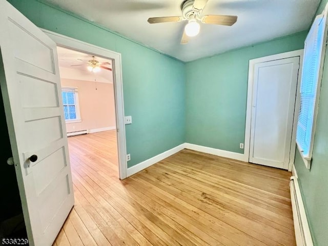 unfurnished bedroom featuring baseboard heating, ceiling fan, and light hardwood / wood-style floors