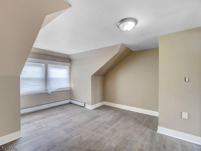 additional living space featuring wood-type flooring, lofted ceiling, and baseboard heating