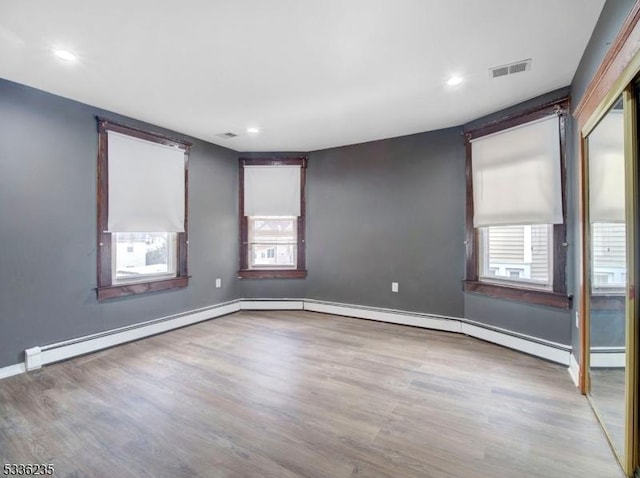 empty room with a baseboard radiator, a healthy amount of sunlight, and light hardwood / wood-style floors