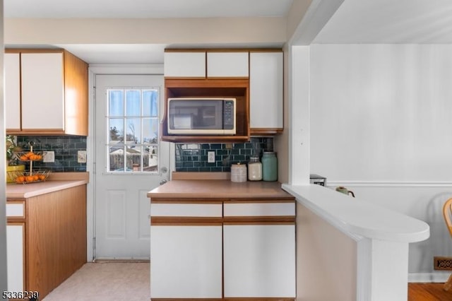 kitchen with decorative backsplash, white cabinetry, and light countertops