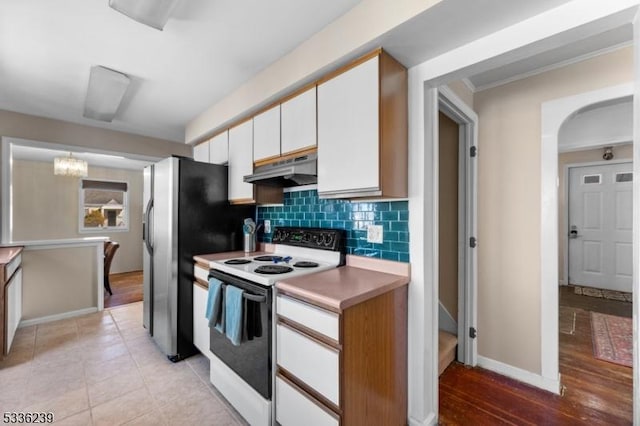 kitchen featuring electric range, arched walkways, decorative backsplash, white cabinets, and under cabinet range hood