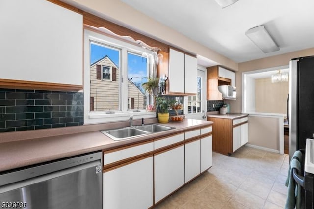 kitchen with a sink, light countertops, white cabinets, appliances with stainless steel finishes, and backsplash