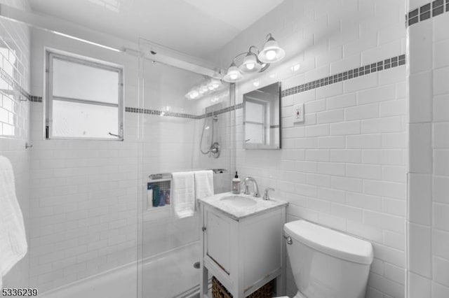 full bathroom featuring vanity, tile walls, toilet, and a stall shower