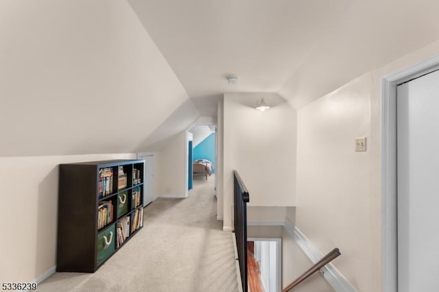 hallway with baseboards, an upstairs landing, lofted ceiling, and carpet flooring