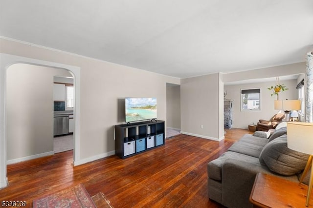 living area featuring wood finished floors, arched walkways, and baseboards