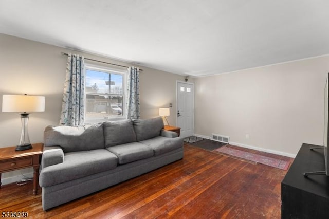 living area featuring visible vents, baseboards, and wood finished floors