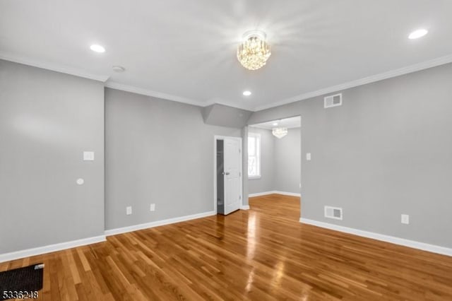 empty room with crown molding, wood-type flooring, and a chandelier