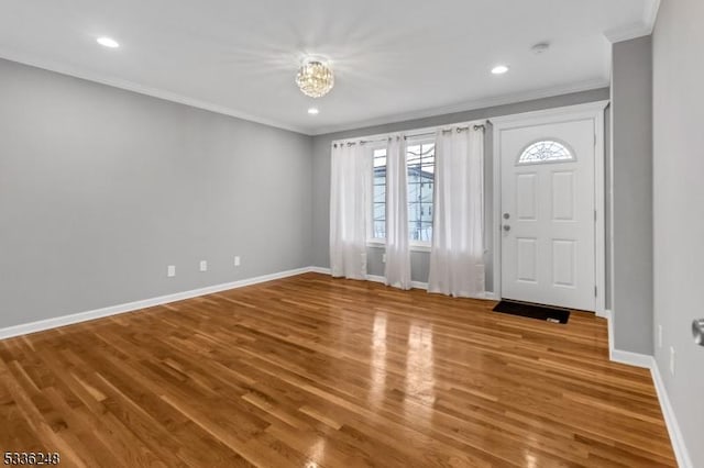 foyer entrance with ornamental molding, wood-type flooring, and a notable chandelier