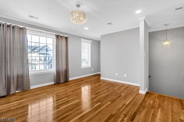 empty room with crown molding, wood-type flooring, and a notable chandelier