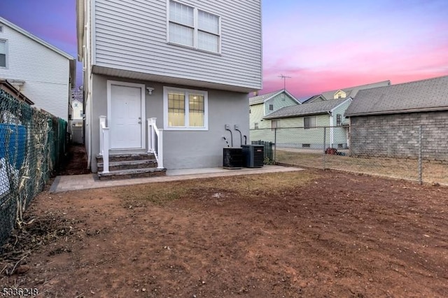 back house at dusk featuring cooling unit