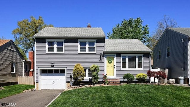 tri-level home featuring a garage, a front yard, roof with shingles, a chimney, and driveway
