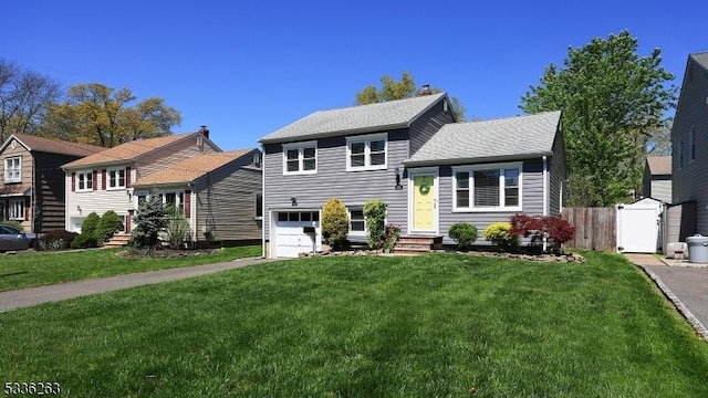 tri-level home with a garage, a front lawn, aphalt driveway, and fence